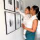 A woman and a girl look at photos on a wall display